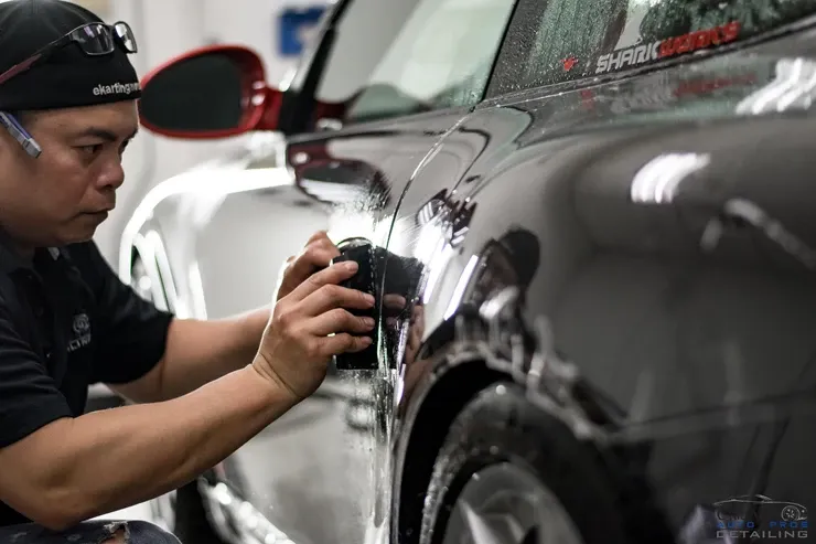 A man is working on the side of a car.