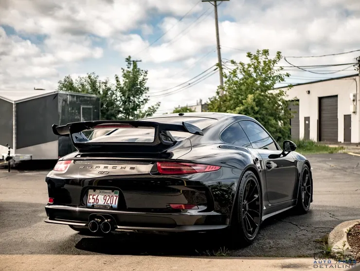 A black porsche 911 gt3 is parked in a parking lot.