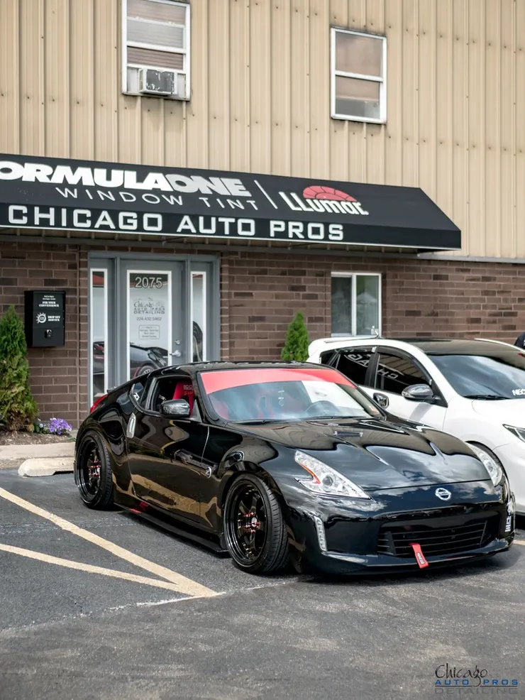 A black car is parked in front of a chicago auto pros building.