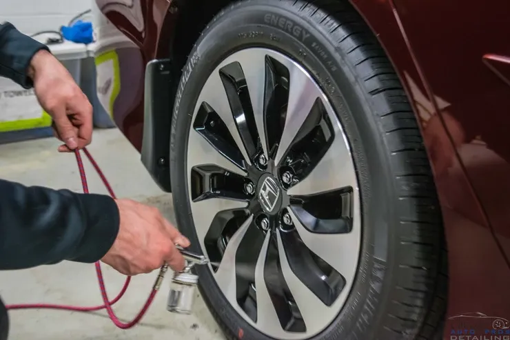 A man is pumping air into a tire of a car.