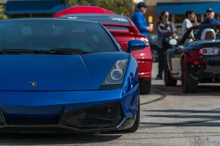 A blue lamborghini is parked in a parking lot next to other cars.