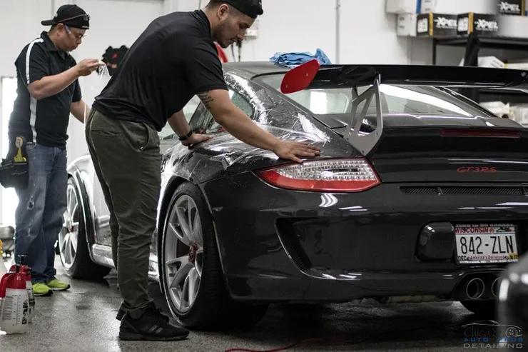 A group of men are working on a car in a garage.