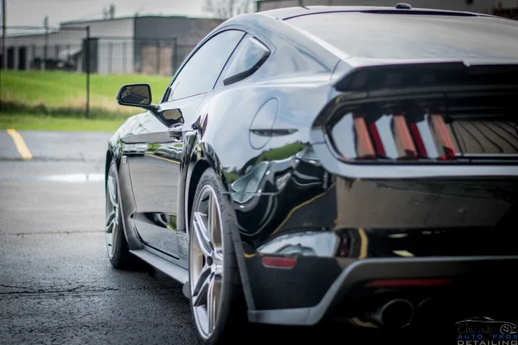 A black ford mustang is parked in a parking lot.