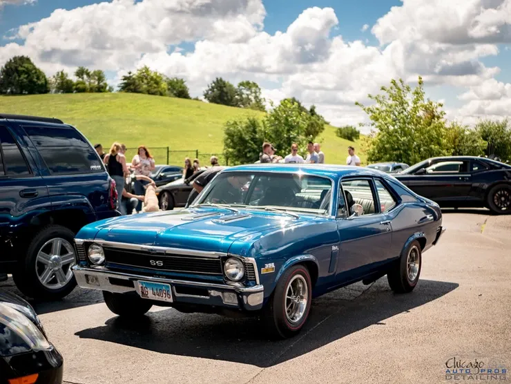 A blue car is parked in a parking lot with other cars.
