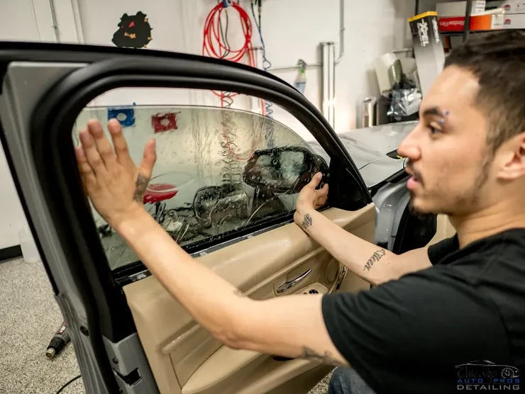 A man is applying window tinting to a car window.