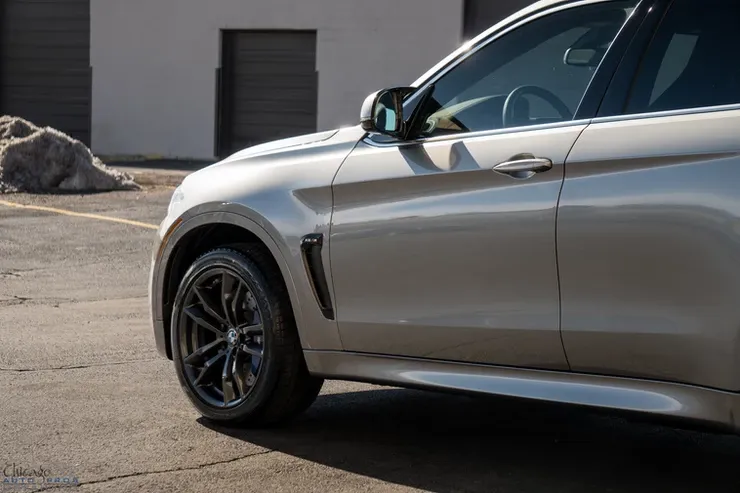 A silver car is parked in a parking lot in front of a building.