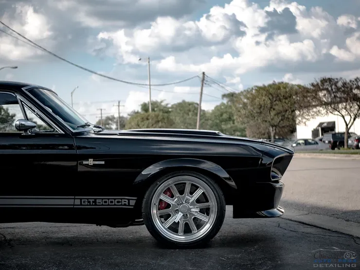 A black mustang is parked on the side of the road.