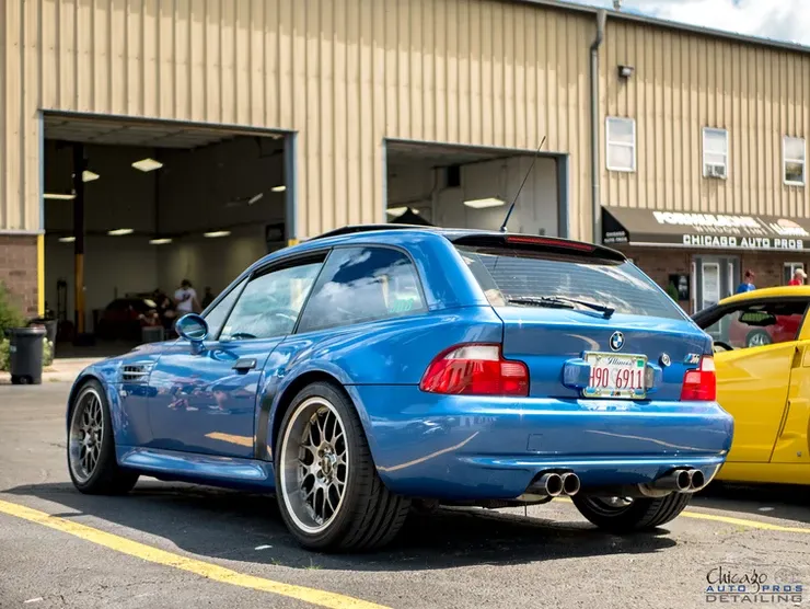 A blue car is parked in front of a building.