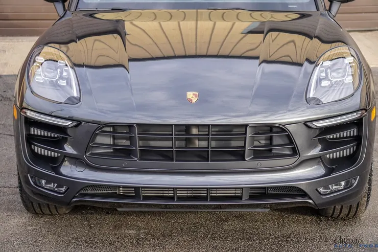 A black porsche macan turbo is parked in front of a garage.