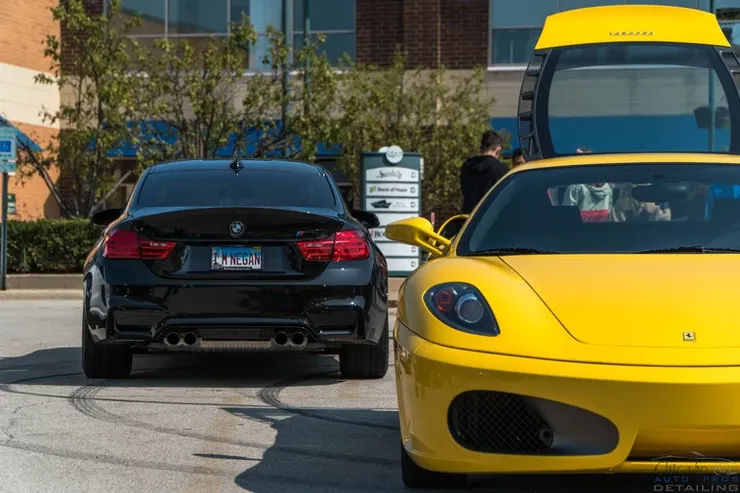 A black car and a yellow car are parked next to each other in a parking lot.