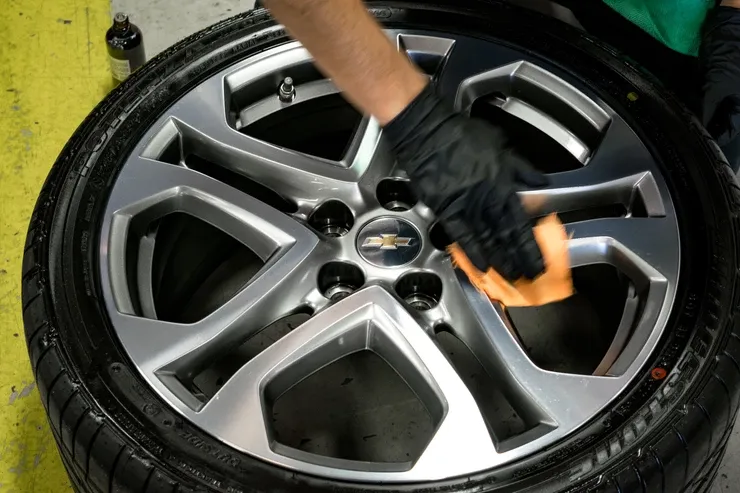A person is cleaning a car wheel with a cloth