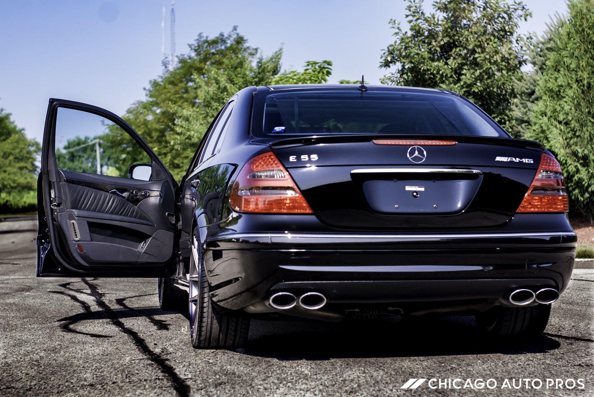 A black mercedes is parked in a parking lot with its doors open
