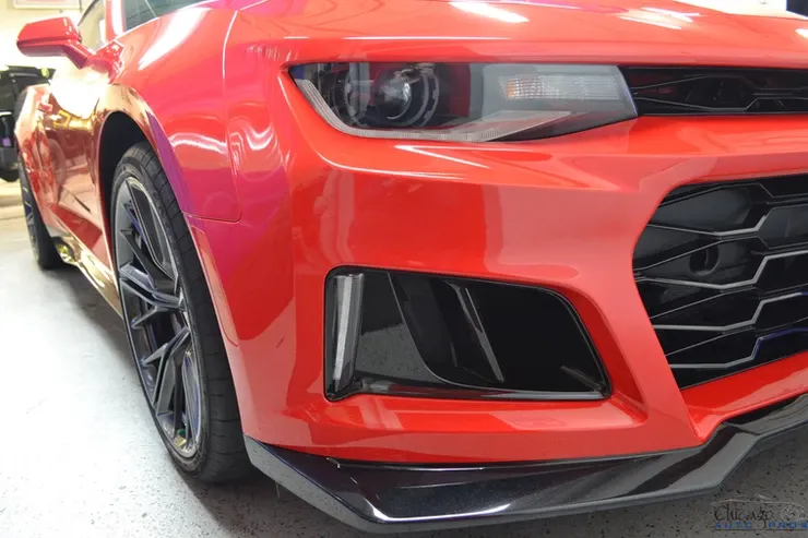 A red car with black wheels is parked in a garage.