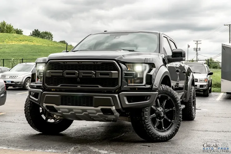 A black ford raptor is parked in a parking lot.