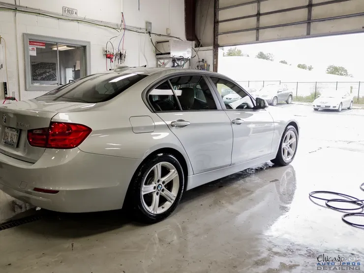 A white bmw 3 series is being washed in a garage.