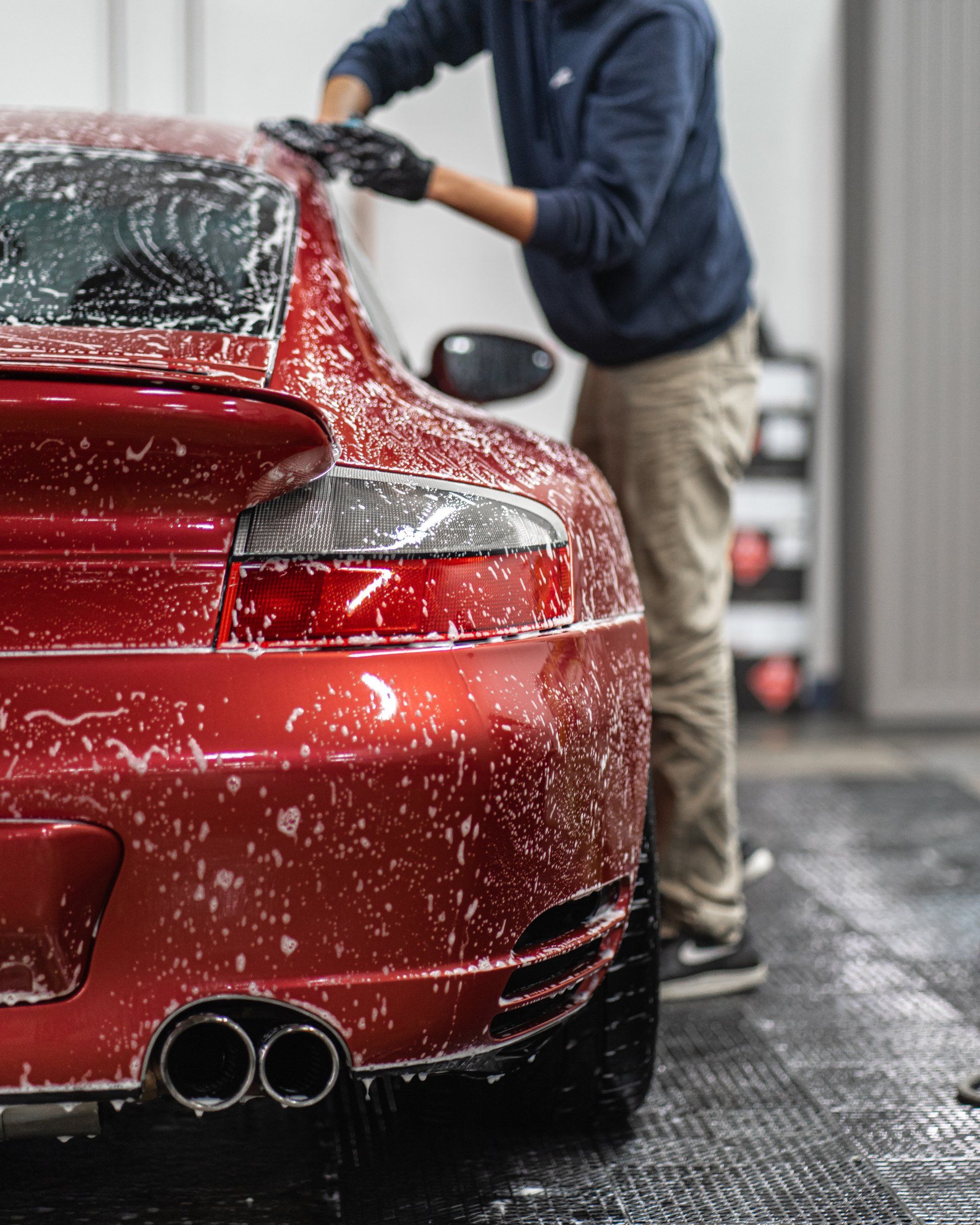 A man is washing a red car in a car wash