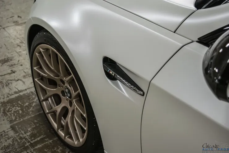 A close up of the side of a white car with gold wheels.