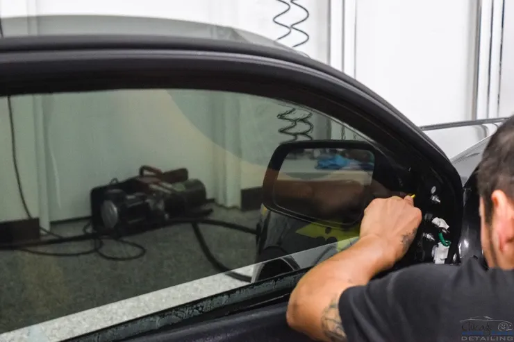 A man is installing window tinting on a car.