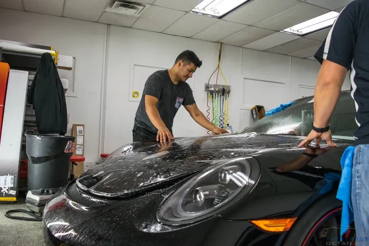 Two men are working on a black car in a garage.
