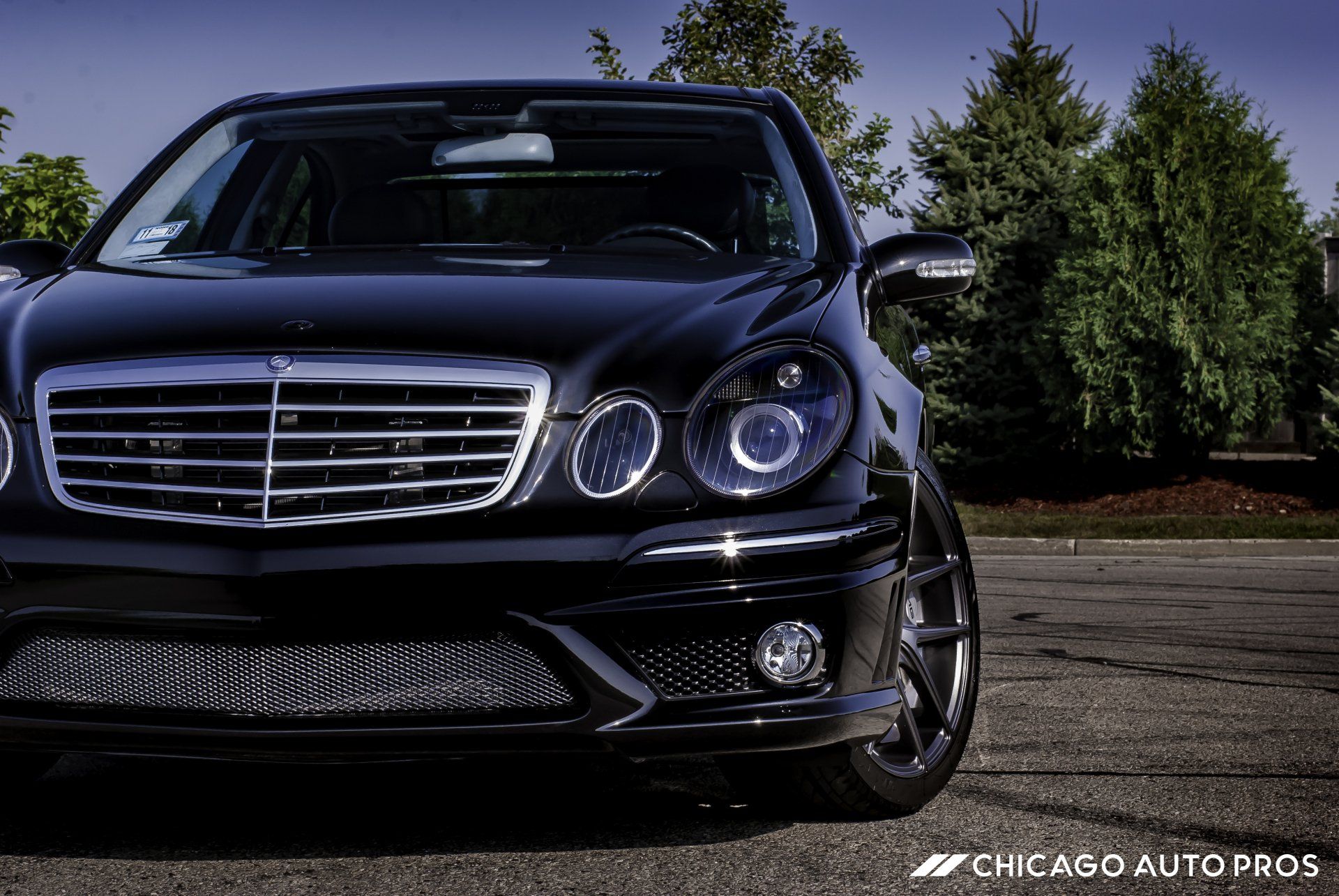 A black mercedes benz is parked in a parking lot