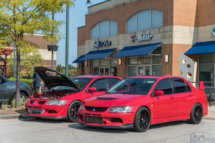 Two red cars are parked in front of a t mobile store