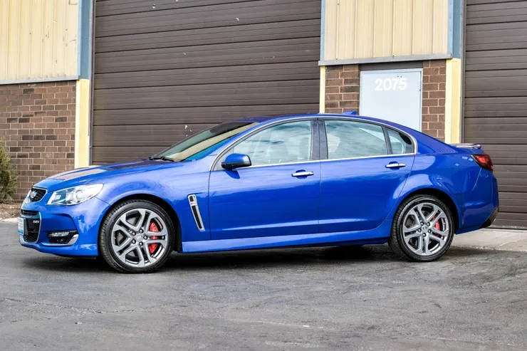 A blue car is parked in front of a garage door.