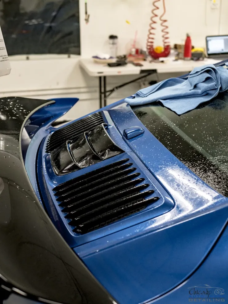 A blue car with a blue cloth on the windshield