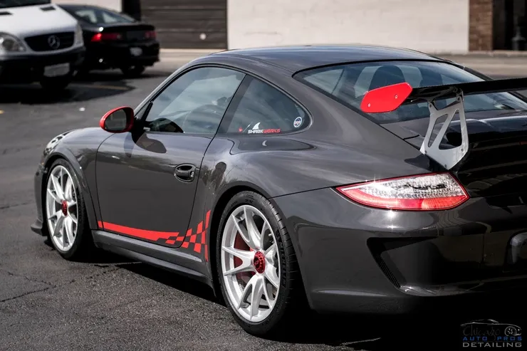 A black sports car with a red stripe on the side is parked in a parking lot.