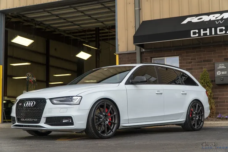 A white audi a4 is parked in front of a garage.