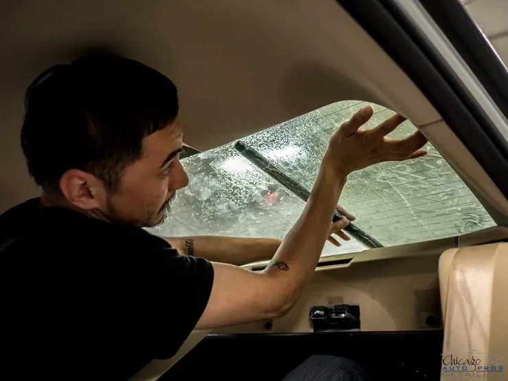 A man is applying window tinting to a car window.
