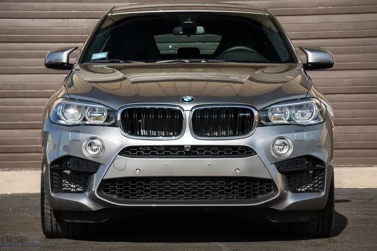 A bmw x5 m is parked in front of a garage door.