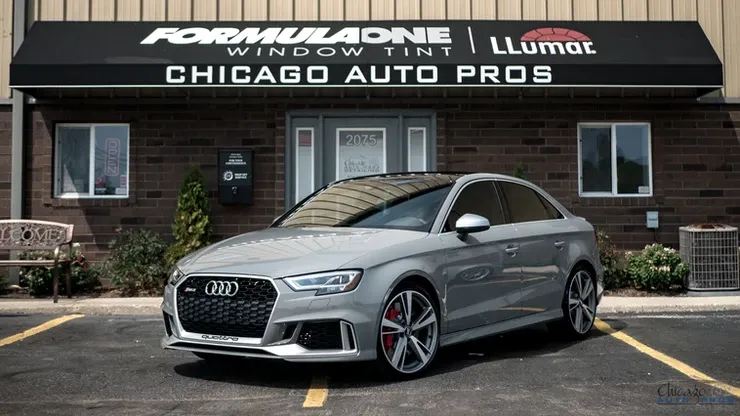 A silver car is parked in front of a chicago auto pros store.