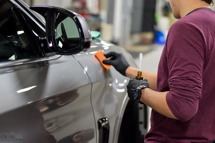 A man is polishing the side of a car with a sponge.