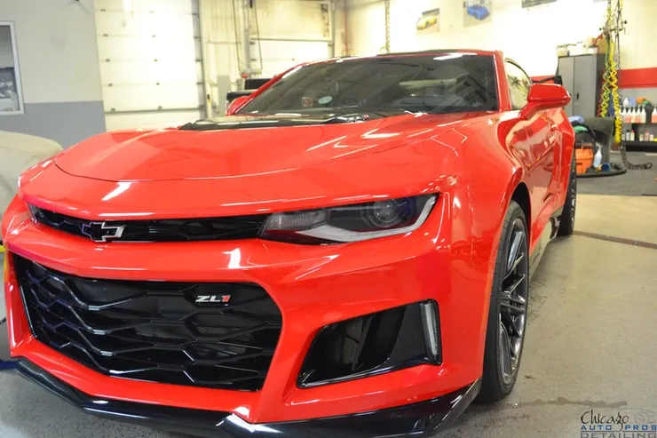 A red chevrolet camaro zl1 is parked in a garage.