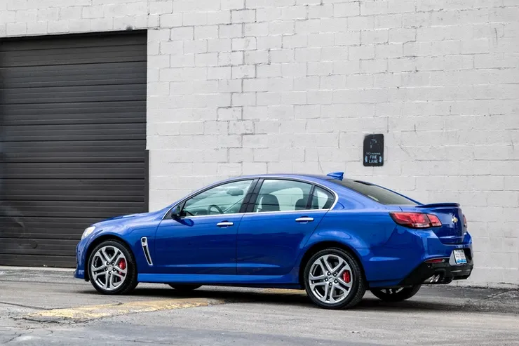 A blue car is parked in front of a garage door.