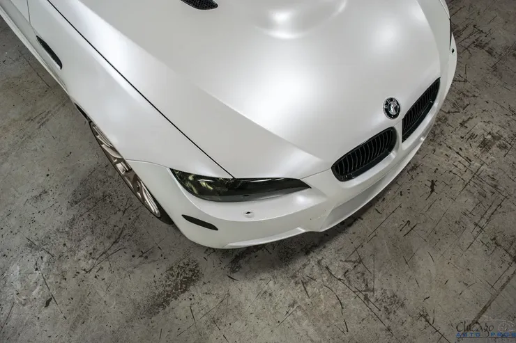 A white bmw is parked on a concrete floor.