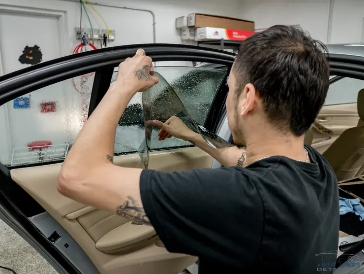 A man is applying window tinting to a car window.