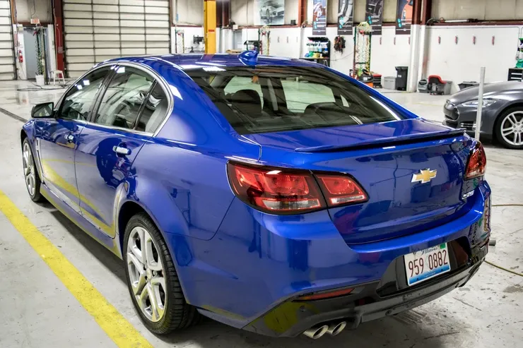 A blue chevrolet sedan is parked in a garage.