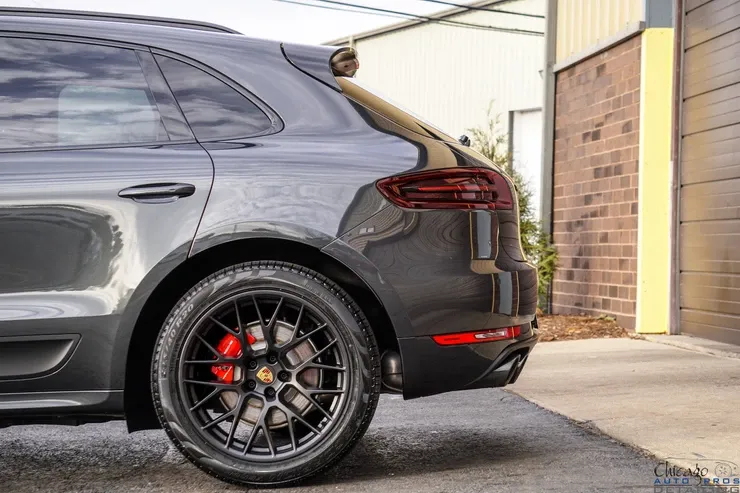 A black porsche macan turbo is parked in front of a brick building.