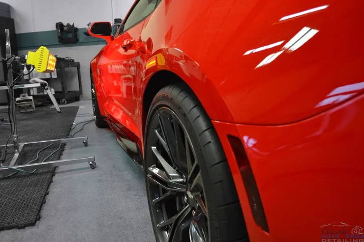 A red sports car is parked in a garage