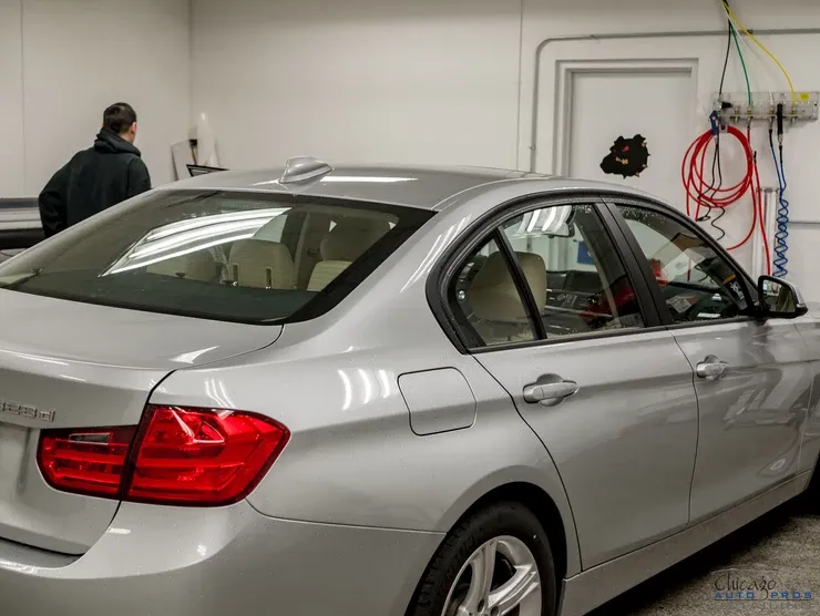 A silver car with a red tail light is parked in a garage.