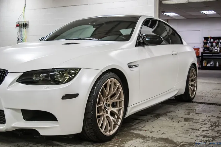 A white bmw m3 is parked in a garage.