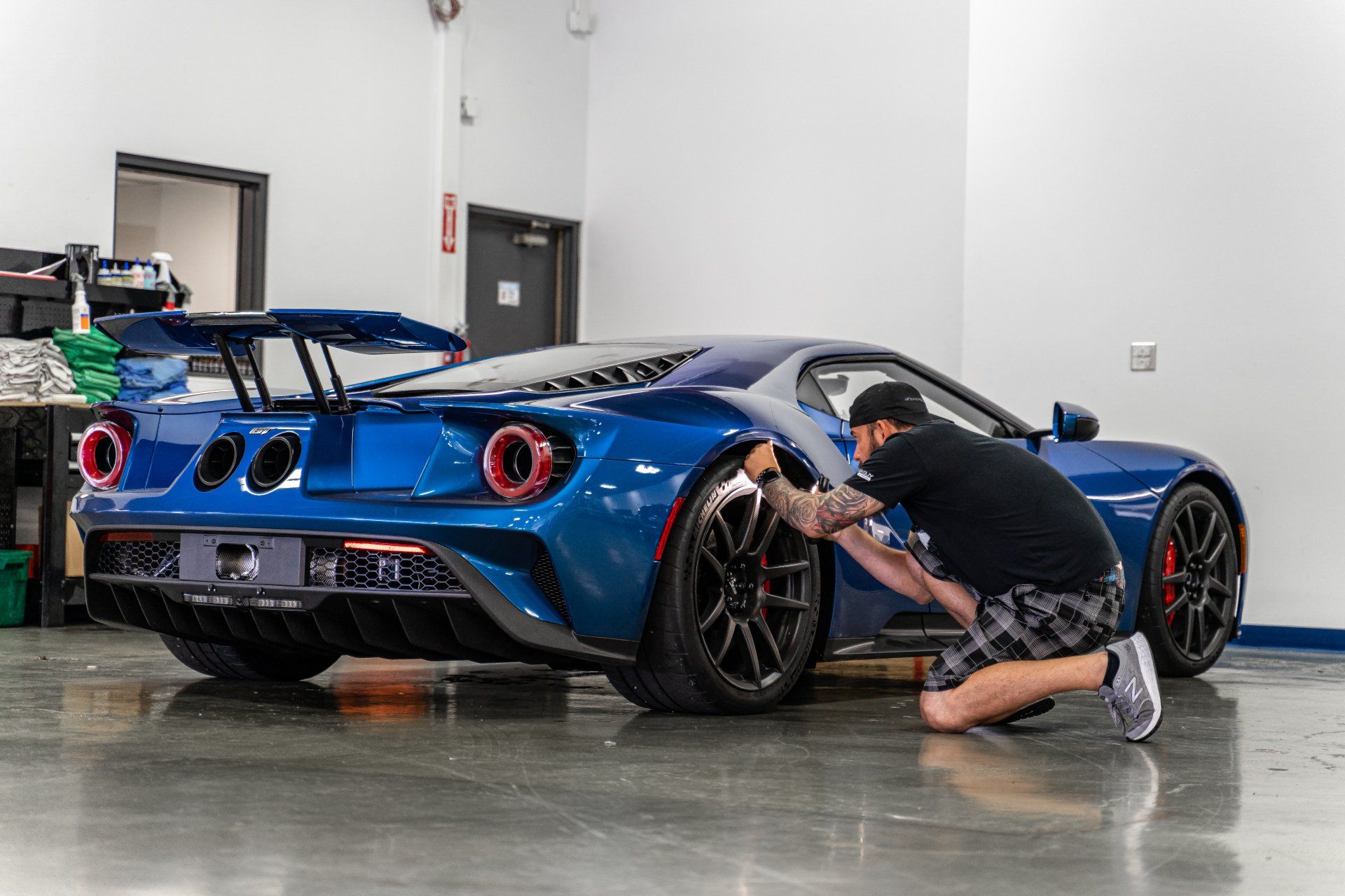 A man is working on a blue sports car in a garage.