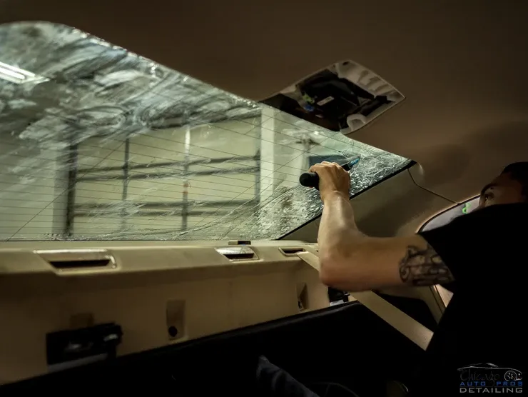 A man with a tattoo on his arm is cleaning the windshield of a car