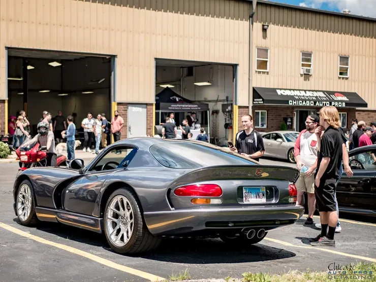 A group of people are standing around a dodge viper parked in a parking lot.