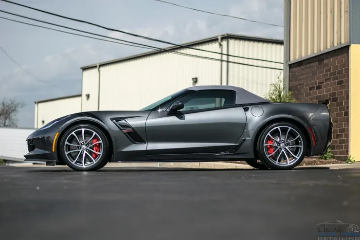 A gray corvette zr1 is parked on the side of the road in front of a building.