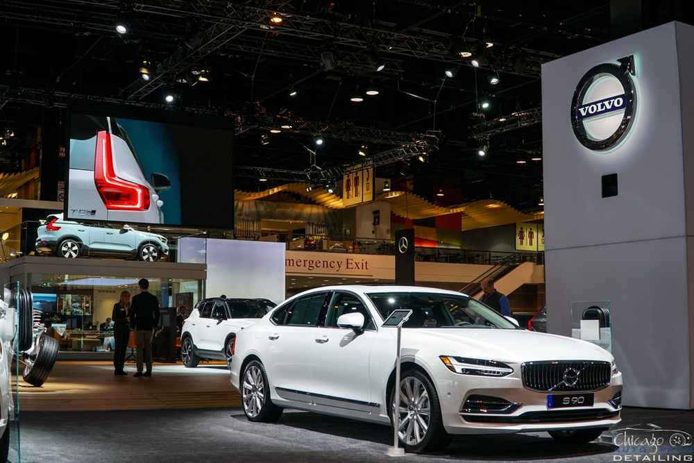 A white volvo car is on display at a car show.