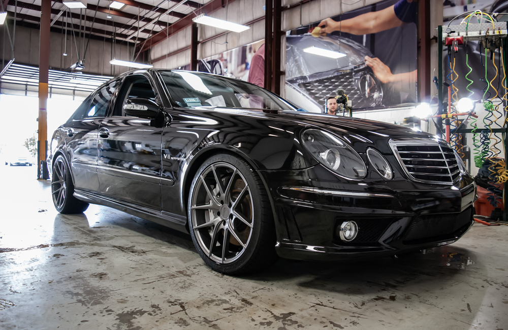 A black mercedes benz is parked in a garage.