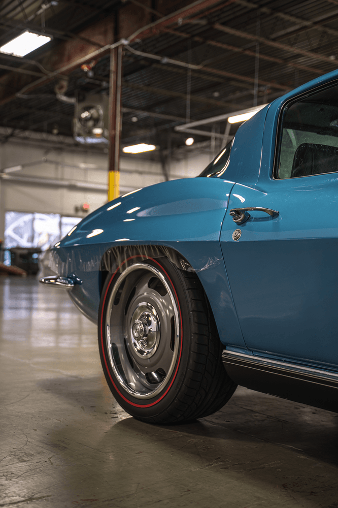 A blue corvette is parked in a garage.