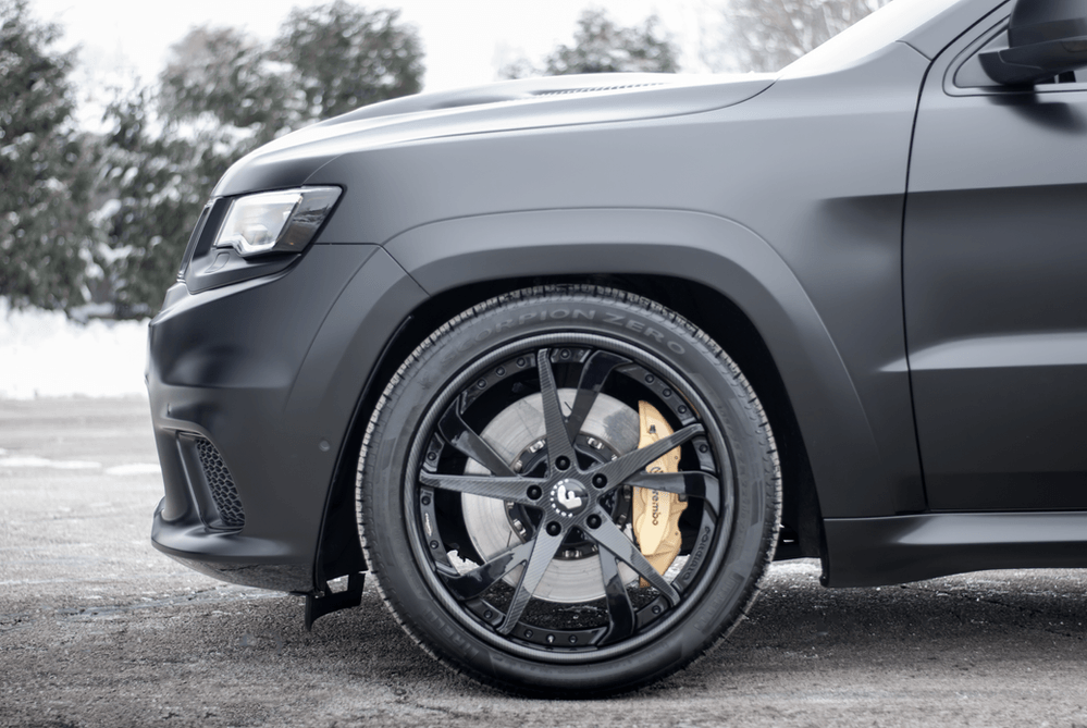 A black jeep grand cherokee is parked in a parking lot.